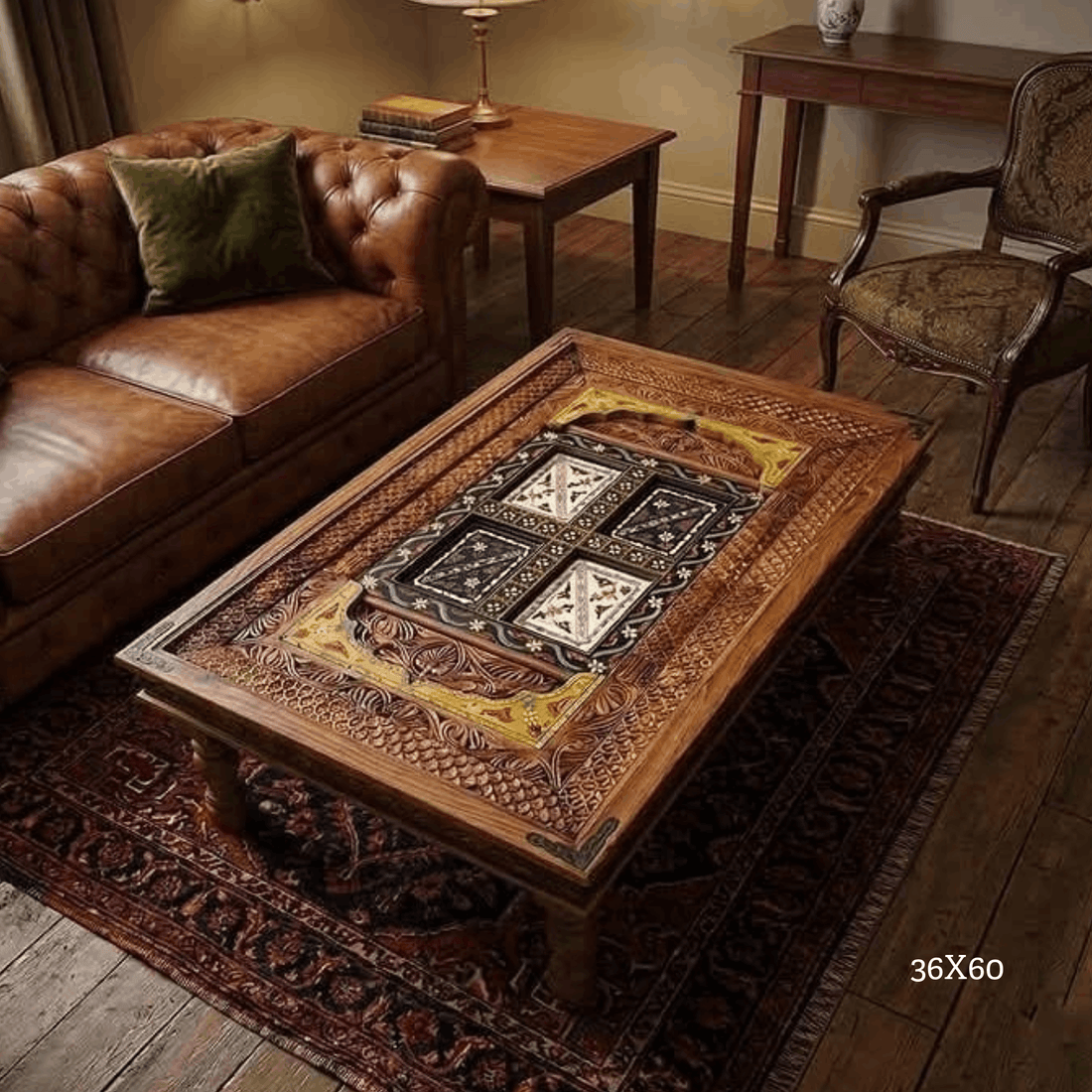 An ornate carved wooden coffee table with a decorative inlay in the center, shown in a styled living room setting with a brown leather sofa, patterned rug, and other furniture.