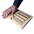 Hand using a wooden roller massager on a white background